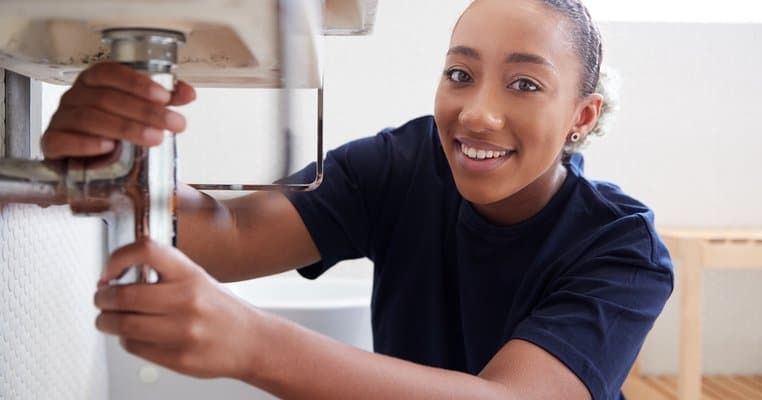 A Woman Fixing a Sink in a Bathroom